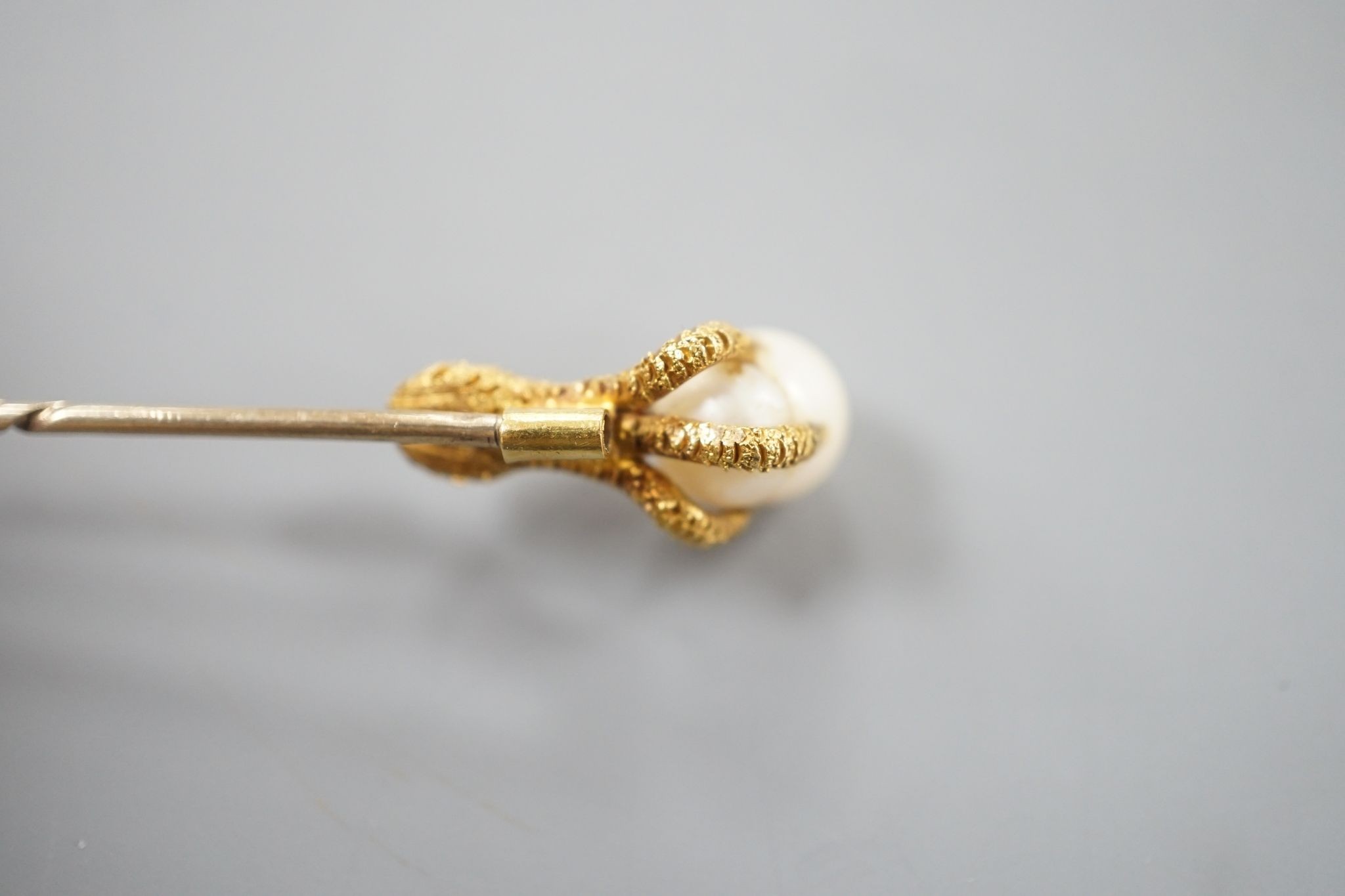 A 19th century yellow metal stick pin, the terminal modelled as an eagle's claw grasping a baroque pearl, 78mm, gross weight 3.3 grams, with box.